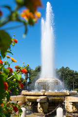 Fototapeta na wymiar Close Up of Fountain in Ebalia Square on Blur Flowers Foreground, in the City of Taranto