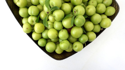 lots of green and sour fresh plums, on white background