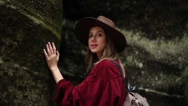Young woman in hat and red shirt near stones in a mountains