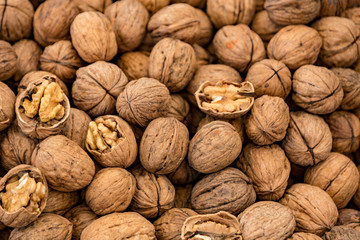 A table filled with walnuts for sale. Some are cracked, to show the interior nut.