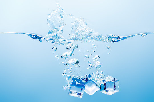 pure water with splash, bubbles and ice cubes on blue background