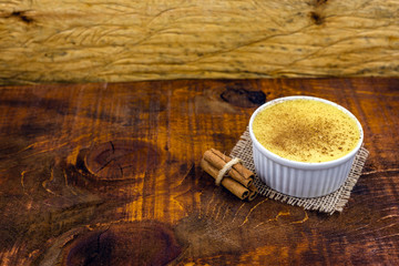 Brazilian sweet corn, corn mousse on a wooden background with copy space. Typical Brazilian dessert, sweet of mingua, called in Brazil of curau. Typical sweet of June party.