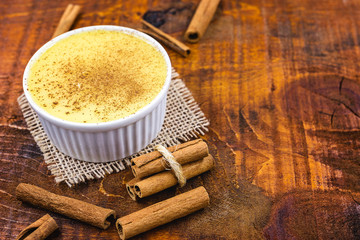 Dessert of curau. Brazilian sweet corn, corn mousse with cinnamon on a wooden background. Typical Brazilian dessert, sweet of June party. Dessert, canjica or Jimbelê.