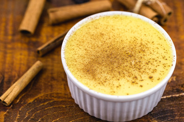 Dessert of curau. Brazilian sweet corn, corn mousse with cinnamon on a wooden background. Typical Brazilian dessert, sweet of June party. Dessert, canjica or Jimbelê.