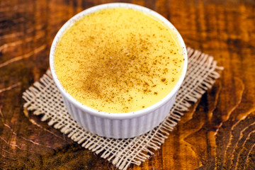 Dessert of curau. Brazilian sweet corn, corn mousse with cinnamon on a wooden background. Typical Brazilian dessert, sweet of June party. Dessert, canjica or Jimbelê.