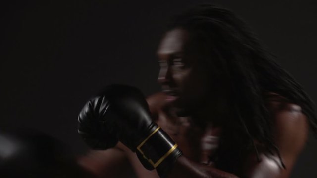 Boxing, African American man boxing in slow motion, black background