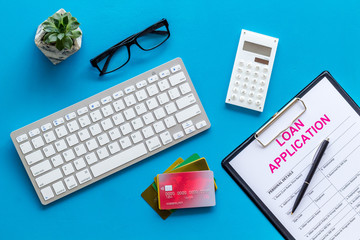 loan application with credit cards and keyboard on banker work place blue background top view