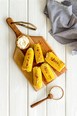 Grilled corn with salt and butter as farm food on white wooden background top view