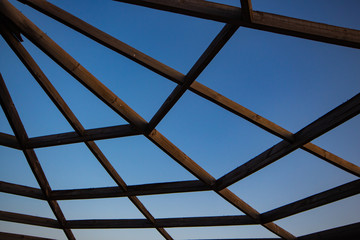 elements of a wooden gazebo against a blue sky