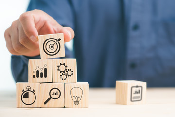 hand of businessman laying wooden blocks with icon business strategy and Action plan, copy space.