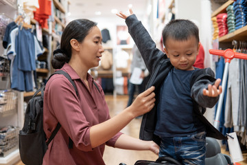 Asian mother is trying to wear a shirt for Her son.In the department store.
