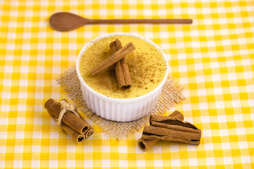 Dessert of curau. Brazilian sweet corn, corn mousse with cinnamon on a wooden background. Typical Brazilian dessert, sweet of June party. Dessert, canjica or Jimbelê.