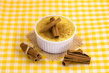 Dessert of curau. Brazilian sweet corn, corn mousse with cinnamon on a wooden background. Typical Brazilian dessert, sweet of June party. Dessert, canjica or Jimbelê.