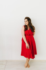 A beautiful caucasian woman wearing a fashion red dress and standing on white backgroung