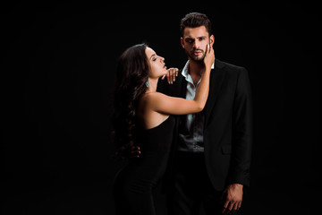 attractive girl touching face of bearded man isolated on black