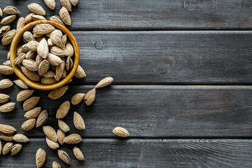 Almond in bowl on wooden background top view space for text