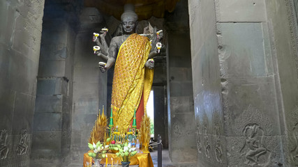 wide shot of a vishnu statue at the entrance to angkor wat temple