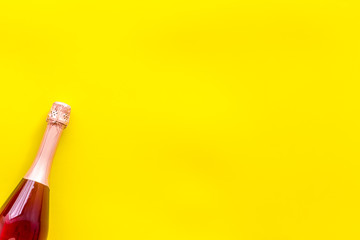 Champagne bottle for celebration on yellow background top view mock up