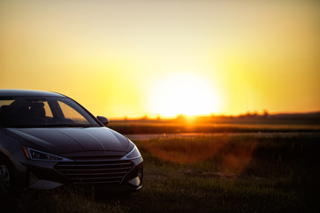 Fototapeta na wymiar Late model new sedan parked in rural north dakota among farms and fields at sunset