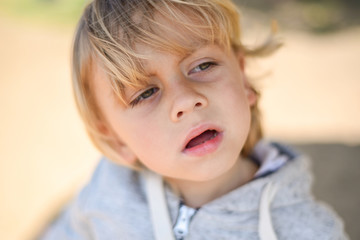 Blond kid walking on the beach in light clothes. Cold summer day. A lonely boy on the river Bank. Emotions. Suffering, unhappiness, sadness, sadness, tears, pain, loss.