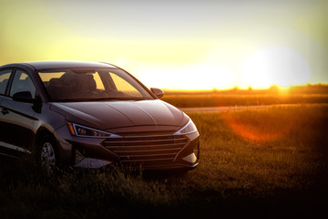 Late model new sedan parked in rural north dakota among farms and fields at sunset