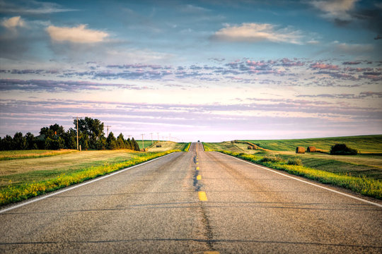 a long country highway rural highway road in North Dakota at sunset with a colorful sky
