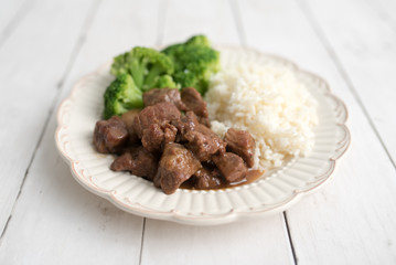 Beef and broccoli Chinese dish over white rice. on a light wood background table