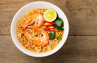 Instant noodles, spicy shrimp soup, spicy, spicy, with Thai spices placed on an old wooden table.