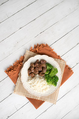 Beef and broccoli Chinese dish over white rice. on a light wood background table