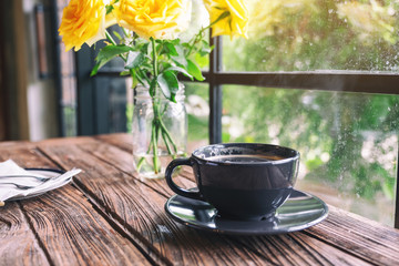 Closeup image of a black cup of hot coffee on vintage wooden table