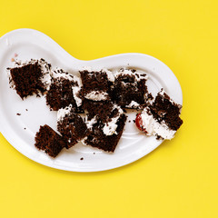 Trash chocolate  cake on yellow  background. Flat lay food vanilla candy art