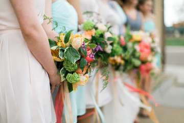 Colorful wedding bouquets, bride and bridesmaids holding wedding flowers, pink and orange ribbons, blue dresses, detail shot