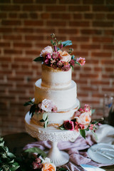 Obraz na płótnie Canvas White wedding cake with pink flowers, peonies, garland on table, greenery, copy space