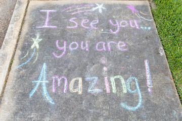 the words "I See You, You are Amazing" written with sidewalk chalk on gray concrete pavement background © Chad Robertson