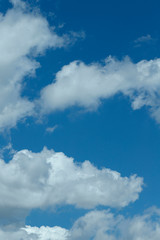 Obraz premium Background of blue sky with white fluffy clouds. Cropped shot, vertical, outdoors, nobody. Concept of nature and ecology.