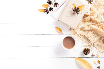 Autumn composition. Cup of coffee gift dried autumn leaves beige sweater on white wooden background. Flat lay, top view copy space.