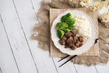 Beef and broccoli Chinese dish over white rice. on a light wood background table