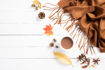 Autumn composition. Cup of coffee, blanket, autumn leaves on white wooden background. Flat lay, top view copy space.