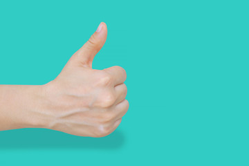 Close up of female hand showing thumbs up gesture over blue pastel background with clipping path. Body language that says ok, all right, good and like sign gesture. Concepts for success and teamwork.