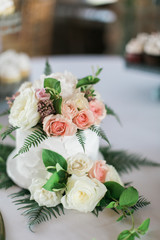 Close up of Small white wedding cake with fresh peonies on top, wedding dessert table