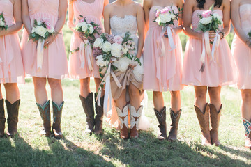 Bride and Bridesmaids wearing cowboy boots, blush pink bridal dresses, white and pink peonies...