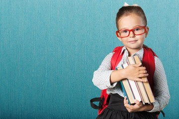 Cute little schoolgirl in glasses on blackboard background