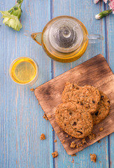 Tasty chocolate chip cookies stacked on a board served with tea and teapot on blue wooden table.Organic homemade snacks for healthy breakfast.Space for text and copy space