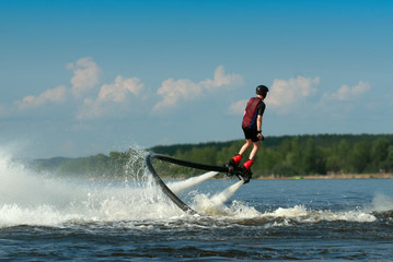 Obraz premium Flight over water. Fly boarding. A fly boarder flies due to the reactive power of water above the surface of the river.