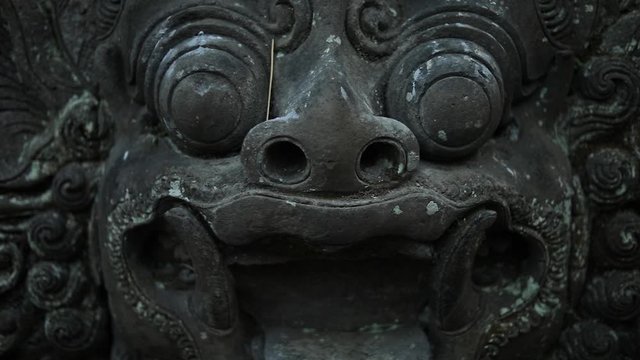 Slow Motion hand-held shot slowly rotating towards an ancient monkey statue at the Sacred Monkey Forest in Bali, Indonesia.