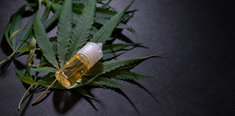 Close-up view of marijuana leaves and cannabis oil bottles