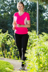 Sporty woman in pink T-shirt is jogging