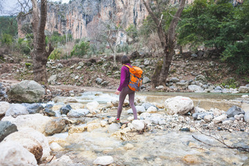 Woman jumps over the mountain river.