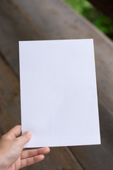 Woman holding paper blank of drawing paper paper with natural background.