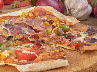 Pizza on thin dough.With slices of salami and ham ,olives and tomatoes.